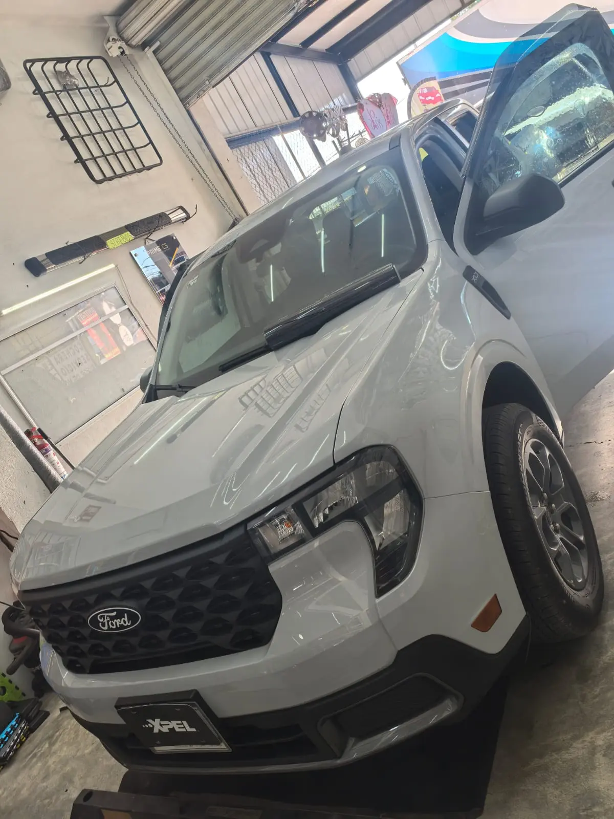 Ford Maverick blanca de frente con puerta abierta en taller