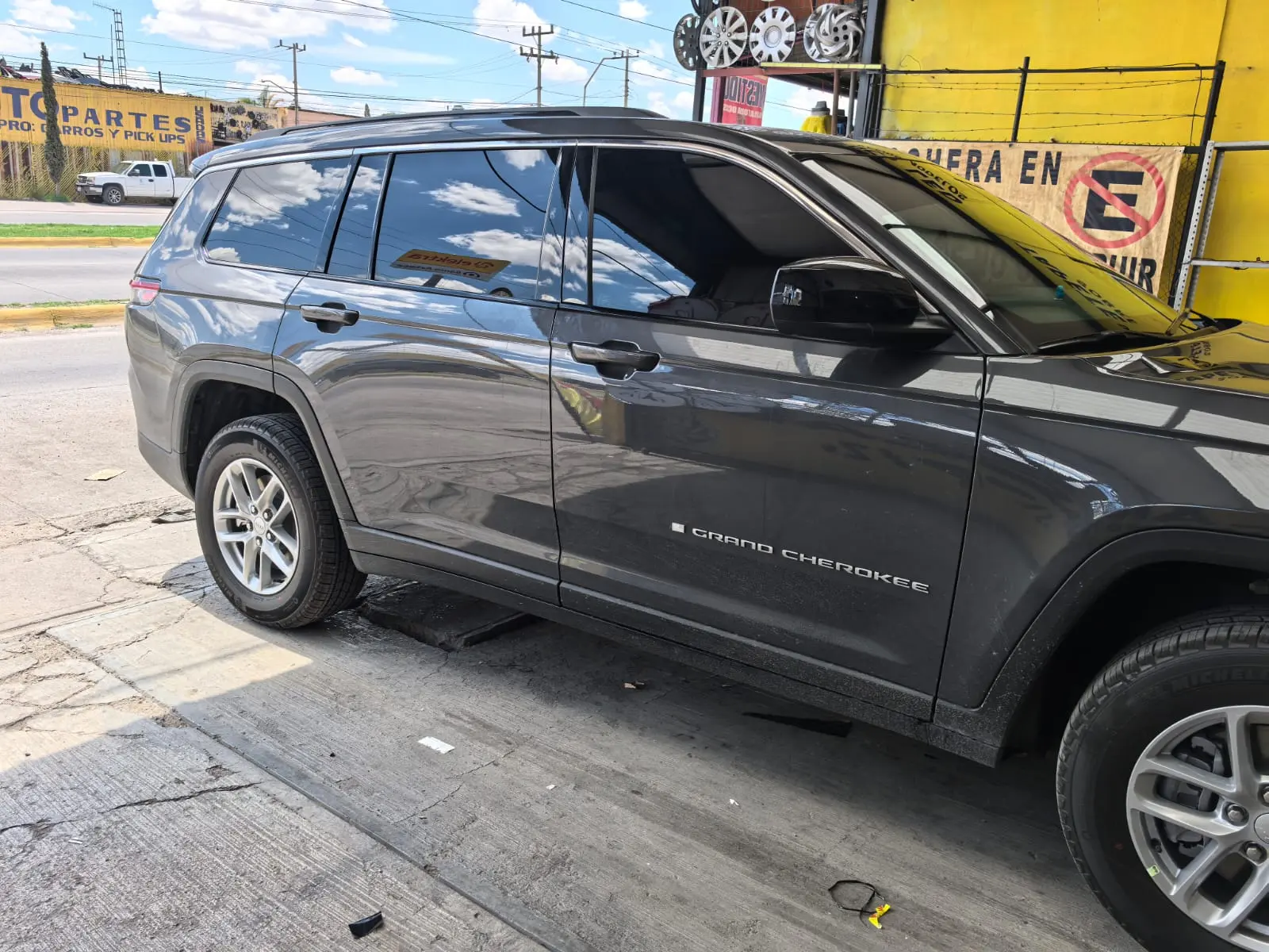Jeep Grand Cherokee gris con vidrios polarizados afuera del taller