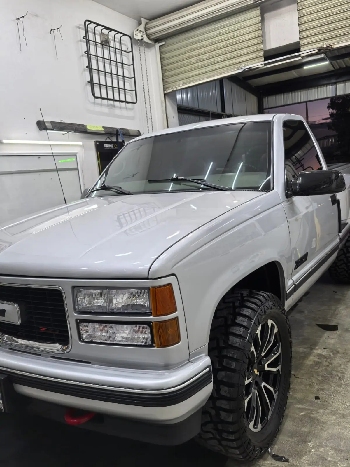 Camioneta clásica GMC Sierra plata con rines deportivos